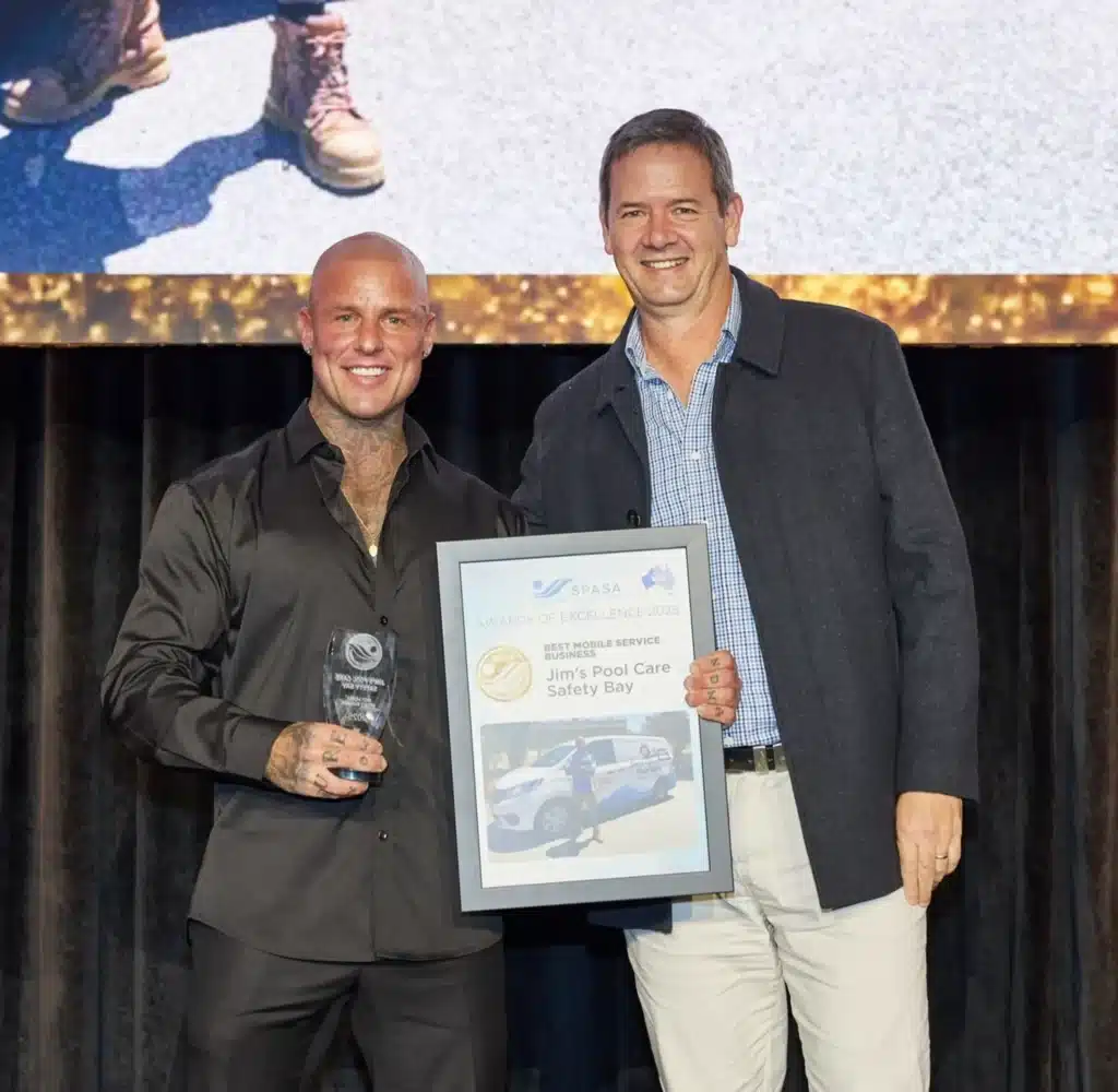 Wayne from Jim's Pool Care Safety Bay accepts an award and trophy on stage with another man.