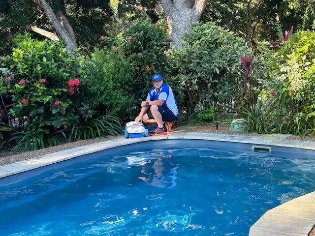 Jim’s Pool Care technician placing a robotic pool cleaner into a Townsville backyard swimming pool