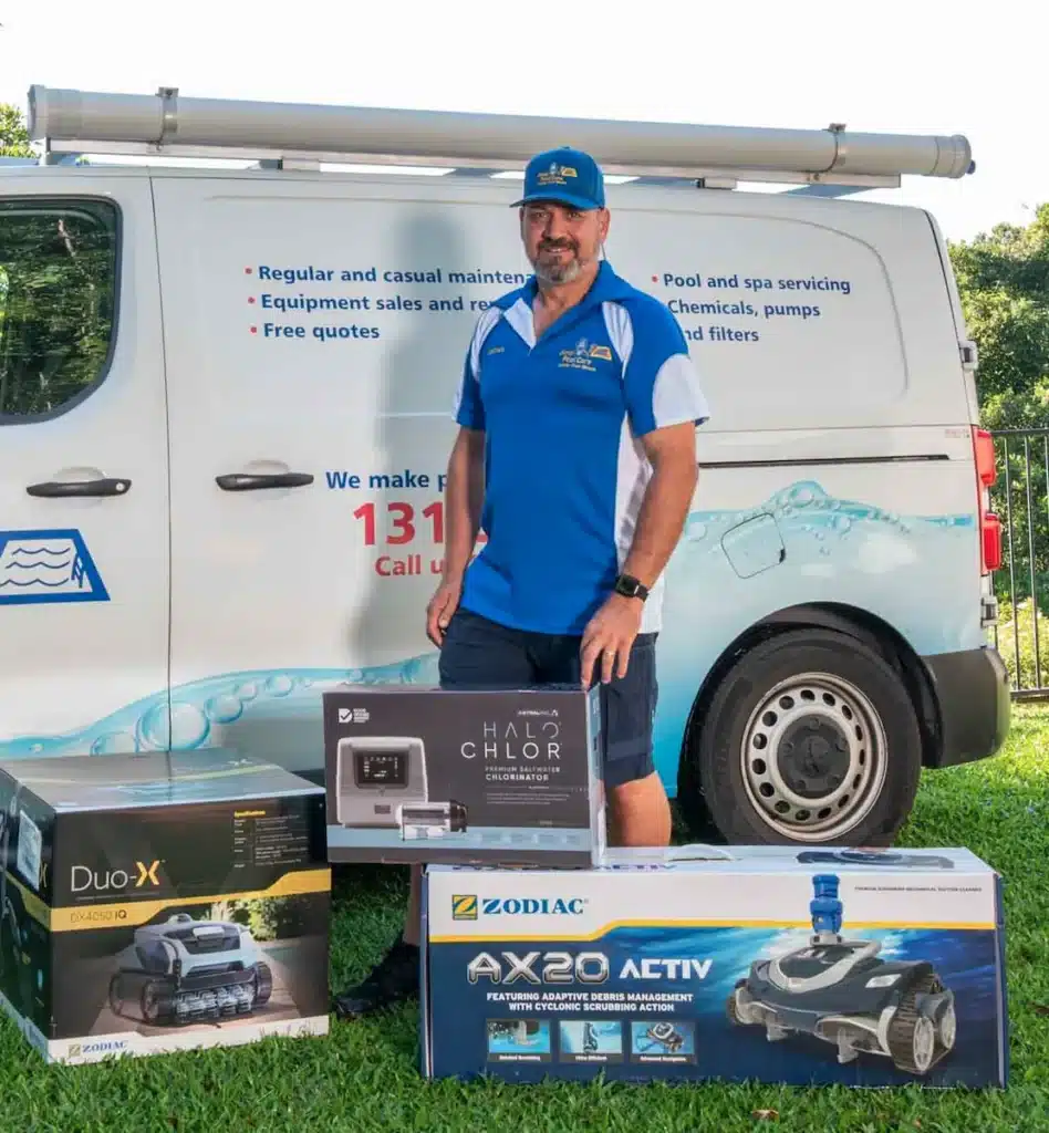 Jim's Pool Care owner operator standing beside a mobile pool shop van with boxed robotic pool cleaners and a chlorinator